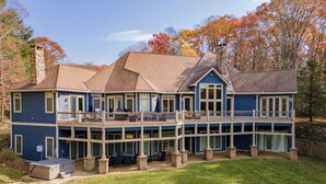 A two-story house with a balcony, a covered patio, and a stone chimney. - Cozy Lake Retreat w/ Dock, Fire Pit & Views (Oakland)
