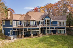 A two-story house with a balcony, a covered patio, and a stone chimney. - Cozy Lake Retreat w/ Dock, Fire Pit & Views (Oakland)