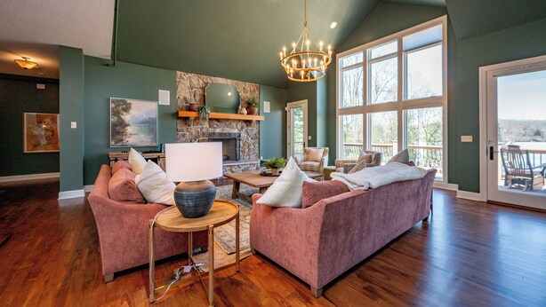 A spacious living room with a fireplace, large windows, and a chandelier. - Cozy Lake Retreat w/ Dock, Fire Pit & Views (Oakland)