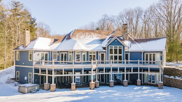 A large, two-story house with a balcony and a chimney, surrounded by snow. - Cozy Lake Retreat w/ Dock, Fire Pit & Views (Oakland)