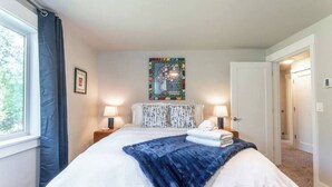 A neatly made bed with a blue blanket, two bedside lamps, and a colorful artwork on the wall. - 5 bed/3 bath with Game Room! (Vancouver)