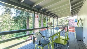 A covered outdoor area with a table and chairs, a railing, and a view of trees and a building in the background. - 5 bed/3 bath with Game Room! (Vancouver)