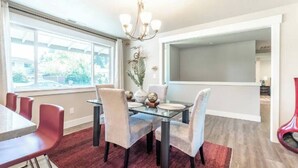 A dining area with a glass table, red chairs, and a chandelier. - 5 bed/3 bath with Game Room! (Vancouver)
