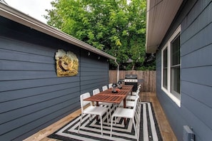 Un cortile con tavolo e sedie di legno, un barbecue e un elemento decorativo a parete.