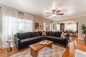 A living room with a sectional sofa, a coffee table, and a ceiling fan.