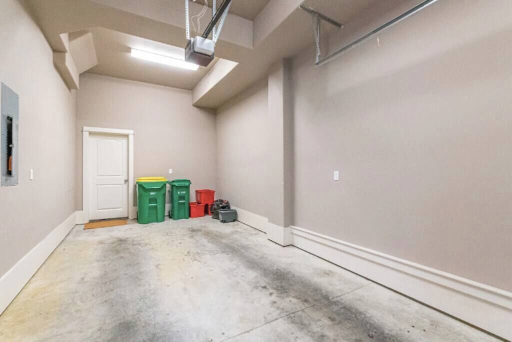 Een schone, lege garage met een witte deur, een betonnen vloer en een plafondlamp.