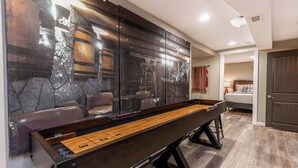 A billiards table in a room with a stone wall and a bed in the background. - 4-bed home w GameRoom, FirePit & Saltwater Hot Tub (Vancouver)