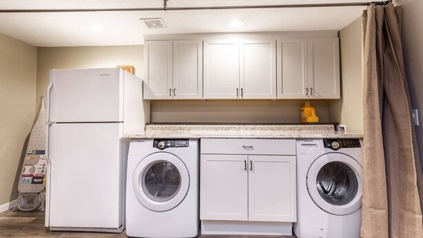 A compact kitchen with a refrigerator, two washing machines, and cabinets. - 4-bed home w GameRoom, FirePit & Saltwater Hot Tub (Vancouver)