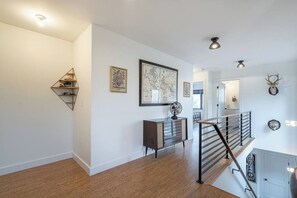A modern interior with a wooden floor, a metal staircase, a console table with a globe, and a large world map on the wall. - Bright and modern 2bd/2.5ba- close to Alberta st! (Portland)