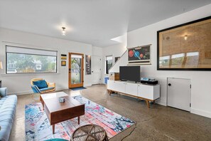 A modern living room with a sofa, coffee table, and a large window. - Bright and modern 2bd/2.5ba- close to Alberta st! (Portland)