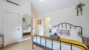 A bedroom with a bed, bedside tables, a mirror, and a hanging plant. - Bright and modern 2bd/2.5ba- close to Alberta st! (Portland)