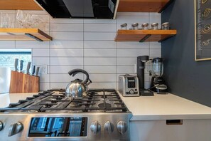 A modern kitchen with a stainless steel gas stove, a kettle, a toaster, and a coffee maker. - Bright and modern 2bd/2.5ba- close to Alberta st! (Portland)