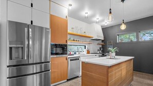 A modern kitchen with stainless steel appliances, wooden cabinetry, and a central island.