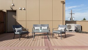 A rooftop terrace with a glass table and two chairs, solar panels, and air conditioning units. - *On Alberta! Modern Artist Loft w/ Rooftop Views!* (Portland)