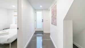 A narrow hallway with a bed on the left and a door at the end. - 2 Bed/1 Bath in NE - Close to Mississippi Ave (Portland)