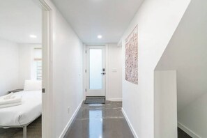 A narrow hallway with a bed on the left and a door at the end.