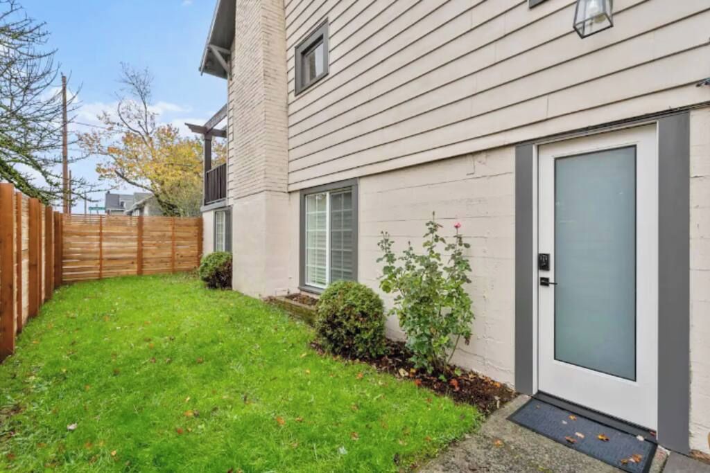 A residential building with a front door, a small front yard, and a wooden fence.