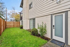 A residential building with a front door, a small front yard, and a wooden fence.