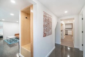 A modern interior with a wooden door, a map on the wall, and a kitchen area visible through an archway.