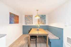 A dining area with a wooden table, two chairs, a bench with cushions, and two abstract paintings on the wall. - 2 Bed/1 Bath in NE - Close to Mississippi Ave (Portland)