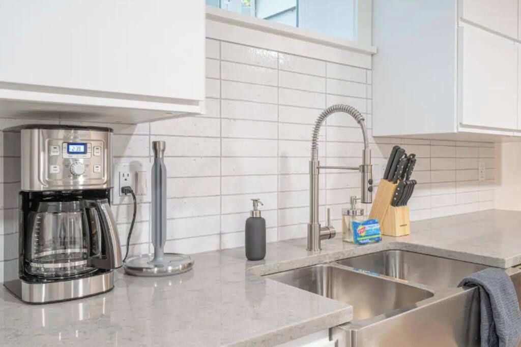 A modern kitchen with a built-in coffee maker, a stainless steel sink, and a knife block.
