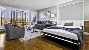 Et moderne hotelværelse med en stor seng, en sofa, et skrivebord og udsigt til det fri.