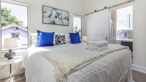 A bedroom with a bed, pillows, a blanket, a lamp, and a painting on the wall. - Modern, Sleek & Stylish: 2 blocks from Hawthorne! (Portland)