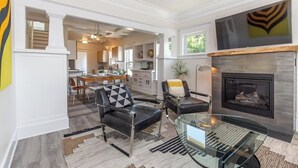 A spacious living room with a fireplace, leather chairs, and a glass coffee table. - Modern, Sleek & Stylish: 2 blocks from Hawthorne! (Portland)