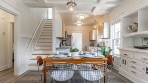 A modern kitchen with a central island, white cabinetry, and a staircase leading to another level. - Modern, Sleek & Stylish: 2 blocks from Hawthorne! (Portland)