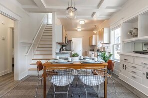 A modern kitchen with a central island, white cabinetry, and a staircase leading to another level. - Modern, Sleek & Stylish: 2 blocks from Hawthorne! (Portland)