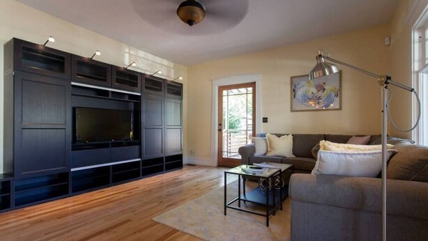 Una sala de estar moderna con un mueble de entretenimiento grande, un sofá, una mesa de centro y una lámpara de pie.