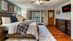 A bedroom with a bed, a ceiling fan, a TV, and a dresser.