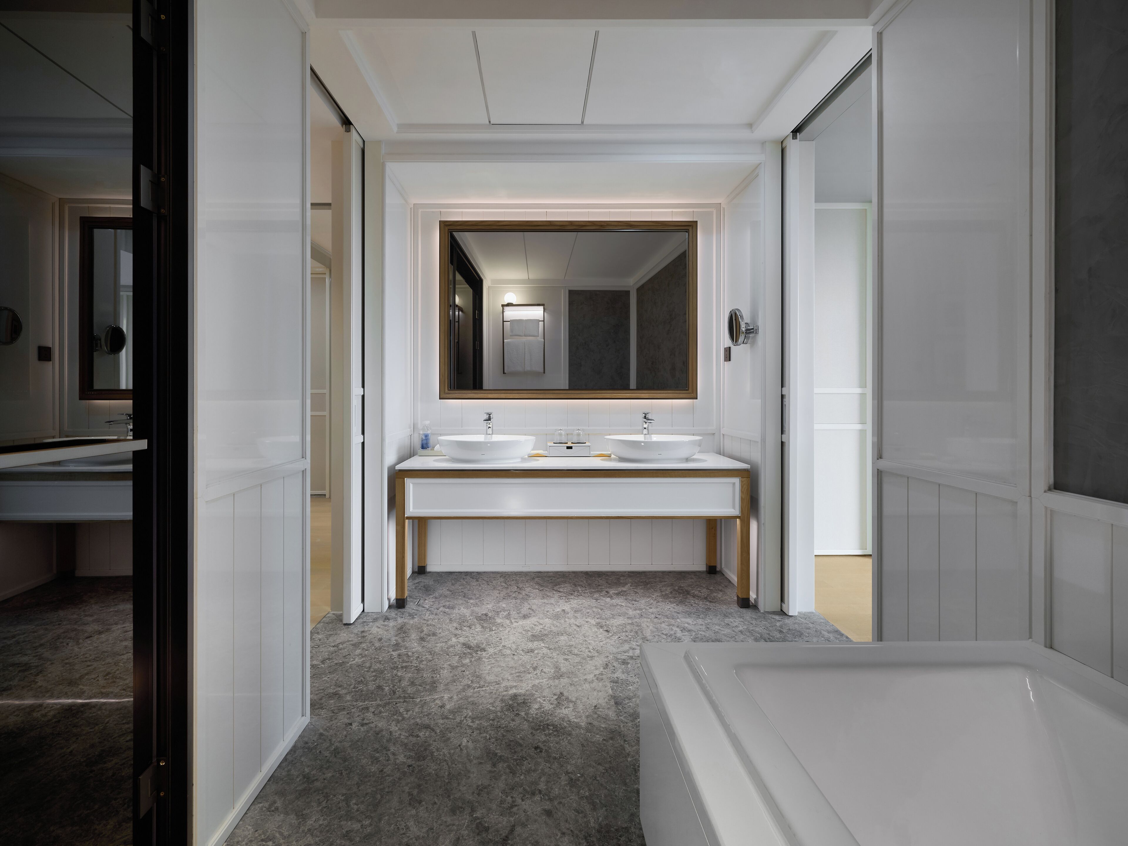 Un baño moderno con tocador doble, un espejo grande y una bañera.