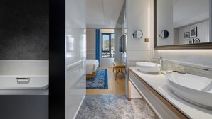 Un baño moderno con un espejo grande, dos lavamanos y una bañera.
