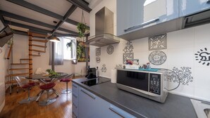 Eine moderne Küche mit Essbereich, ausgestattet mit einer Edelstahl-Mikrowelle, einer Kaffeemaschine und einer Holzleiter.