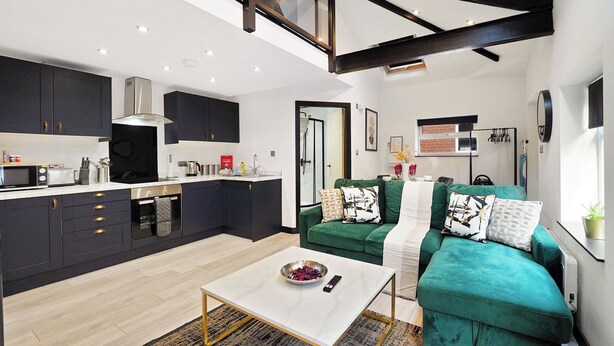 A modern kitchen with dark cabinetry, a white countertop, and a built-in oven. - Elegant Yorkshire Abode - Great Location - Sleeps 19 (Castleford)