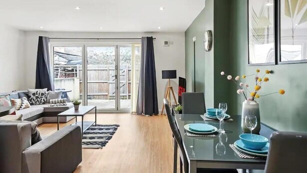 Una sala de estar moderna con sofá, mesa de comedor y vistas a través de un ventanal.