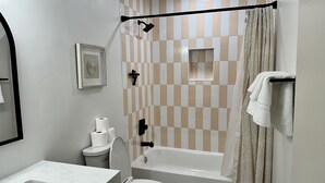 Ein Badezimmer mit Toilette, Waschbecken, Badewanne, Dusche und einem Handtuchhalter.