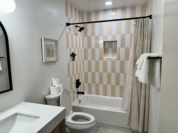 A bathroom with a toilet, sink, bathtub, shower, and a towel rack.