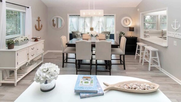 A dining area with a chandelier, white furniture, and nautical decor.