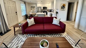 A modern living room with a red sofa, a wooden coffee table, and a ceiling fan. - 2 King Beds + 400ft from Beach - 8 (norfolk)
