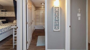 Un dormitorio con literas, una escalera, ducha y un pasillo con un letrero que dice 'RELAY'.