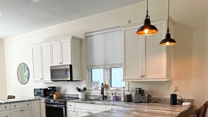 Een moderne keuken met witte kasten, een centraal eiland en hanglampen.