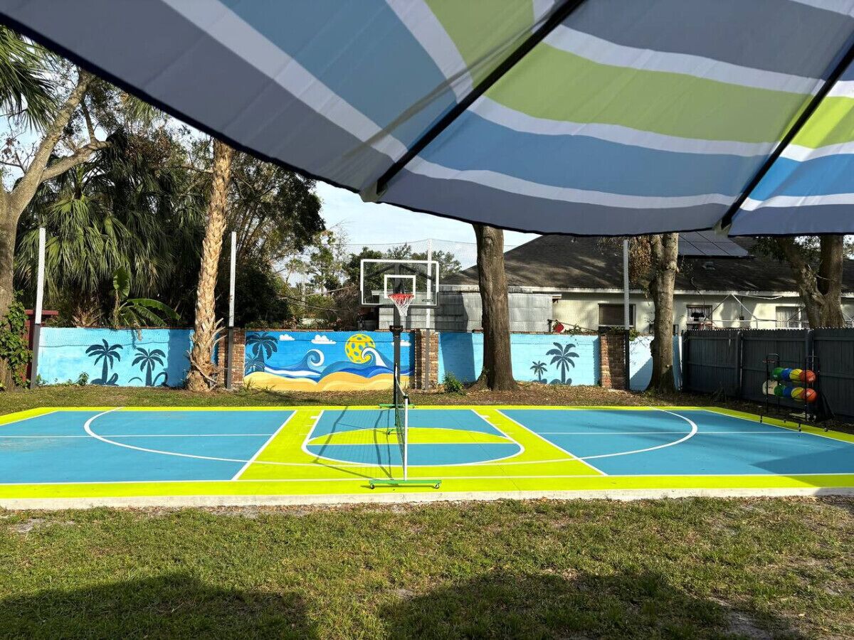 An outdoor basketball court with a colorful mural in the background.