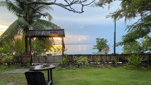 A gazebo with a view of the sea, a table with chairs, and a grassy area. - Charming beach front villa  for 2  guess max, with Starlink internet in GL (General Luna)