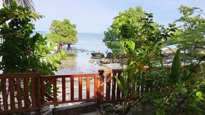 A wooden gate leading to a beach with clear water and rocky shore, surrounded by lush greenery. - Charming beach front villa  for 2  guess max, with Starlink internet in GL (General Luna)