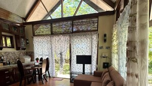 A spacious living area with a large sofa, a dining table with chairs, and a kitchen area with cabinets and a window. - Charming beach front villa  for 2  guess max, with Starlink internet in GL (General Luna)