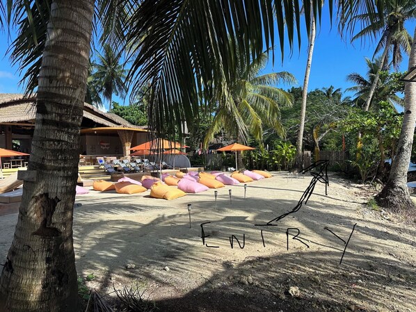 A beachside resort with lounge chairs, umbrellas, and a sandy area.