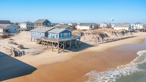 Ein Hotel direkt am Strand mit einer Holzterrasse, feinem Sand und blauem Himmel.