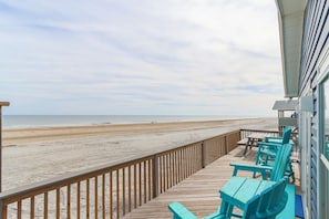 Une terrasse en bois avec une rambarde donnant sur une plage.